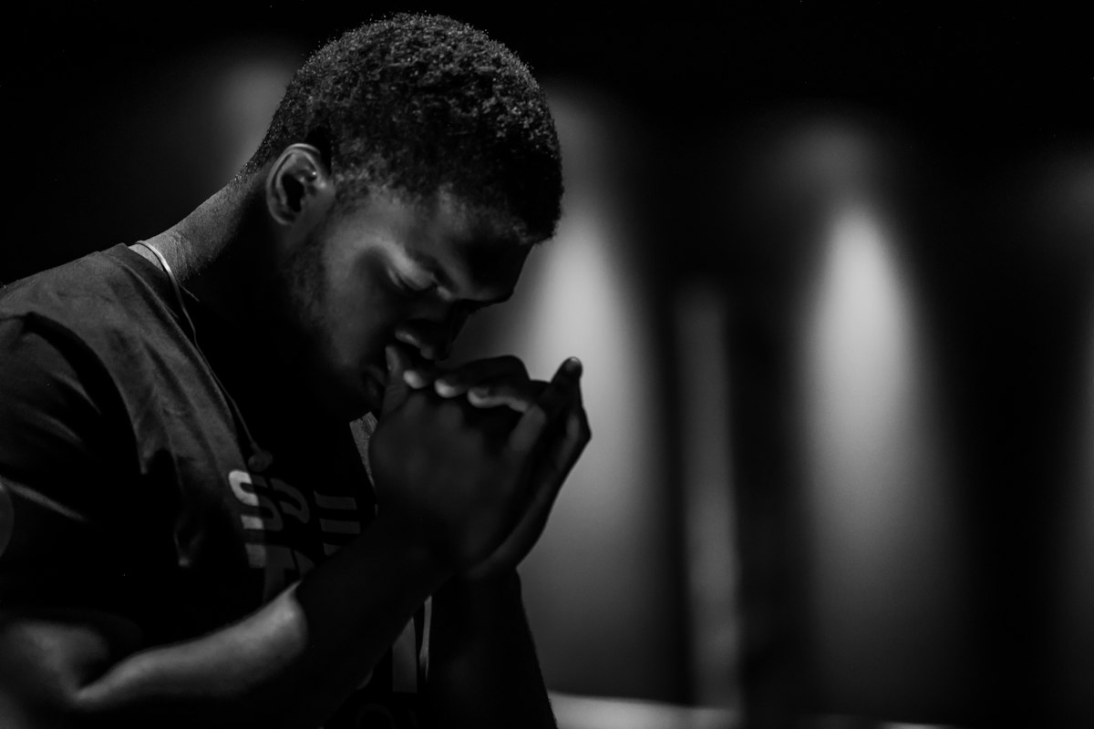 A man in still, contemplative prayer with hands clasped and head bowed